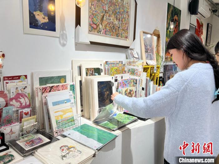 圖為藝術(shù)品商店內(nèi)，顧客挑選插畫作品?！＄婌?攝