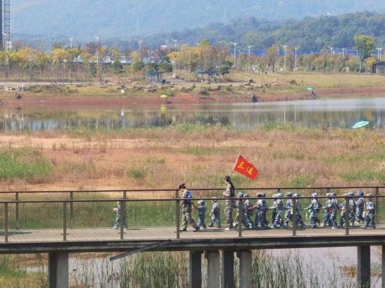 　　10月24日，秋游的幼兒園小朋友在老師帶領下走在清水塘公園里的木橋上。本報記者 常雯宜攝