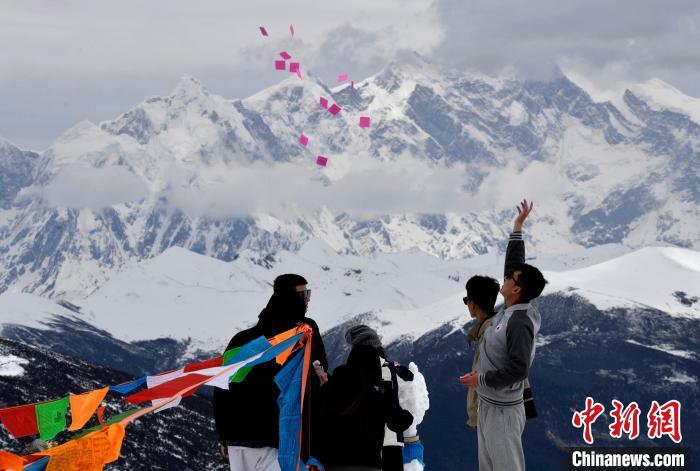 圖為5月14日，游客在西藏林芝色季拉山觀景臺(tái)拋灑“隆達(dá)”(風(fēng)馬旗，藏族民眾的一種祈福方式)。　李林 攝