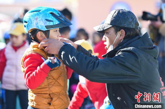 圖為拉薩市實(shí)驗(yàn)幼兒園孩子在教練的幫助下穿戴頭盔?！『闻罾?攝