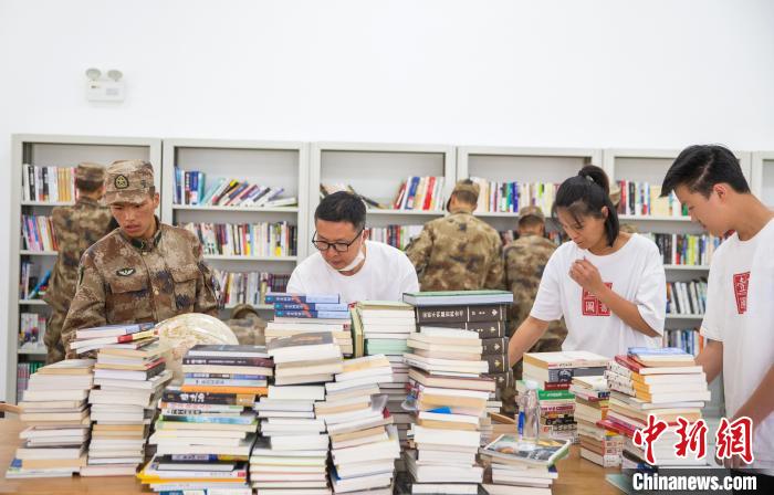 圖為志愿者們和邊防戰(zhàn)士整理圖書?！詵| 攝